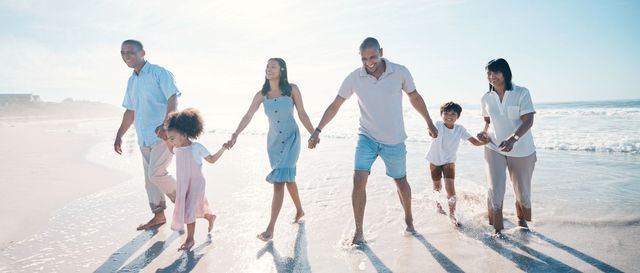 Una familia camina por la playa tomados de la mano.