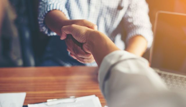 Un hombre y una mujer se dan la mano en una mesa.