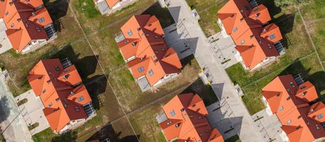 Una vista aérea de una hilera de casas con techos rojos en una zona residencial.